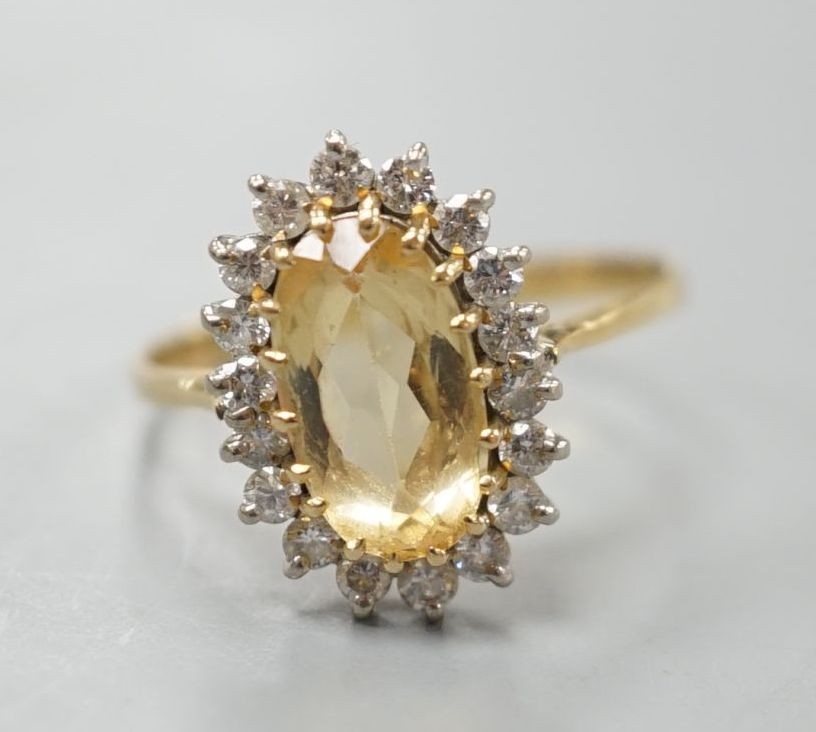 A modern yellow metal, yellow topaz and diamond set oval cluster ring, size T, gross weight 3.7 grams.